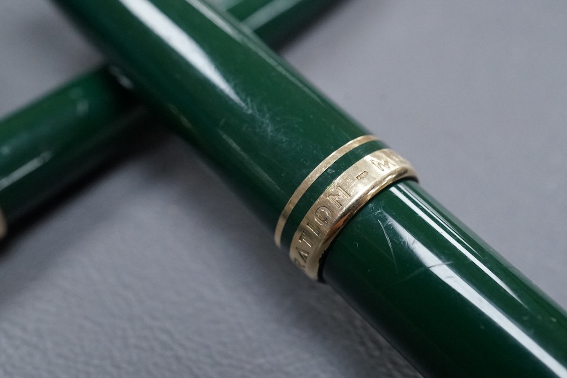 Three Mont Blanc pens in a green leather Mount Blanc case and two inkwells.